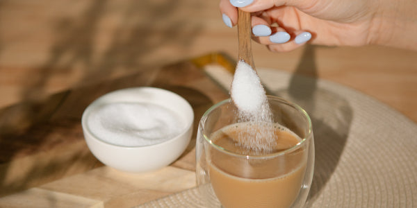 Löffel Erythrit wird in Milch-Kaffee gegeben 